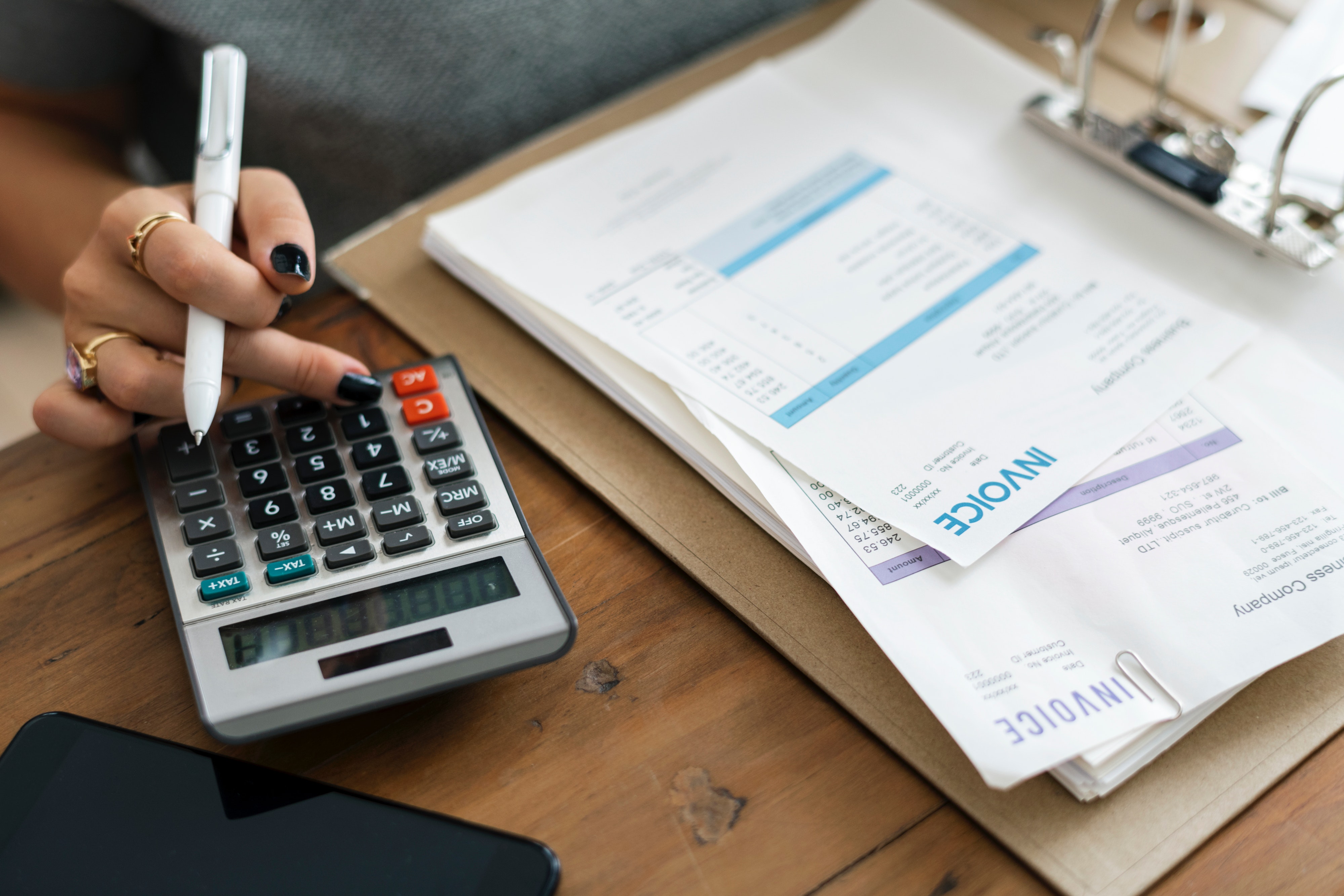 billing invoices and calculator with woman holding a pen.